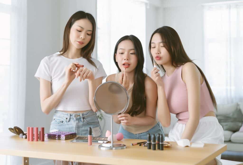young chinese girls applying makeup in front of a mirror