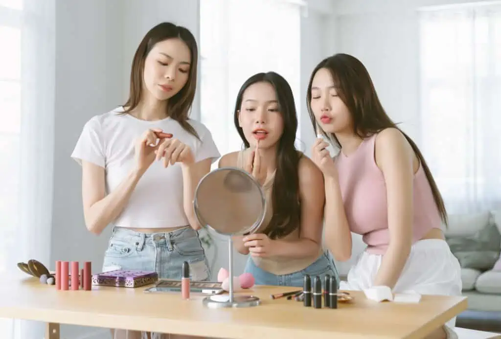 unge kinesiske piger lægger makeup foran et spejl